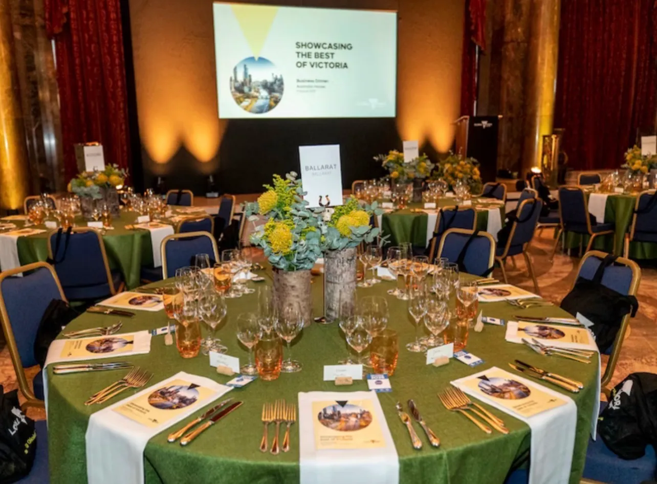 One table laid and waiting, gold cutlery and a printed programme at every place, delegate bags hung on the chairs and the stage behind