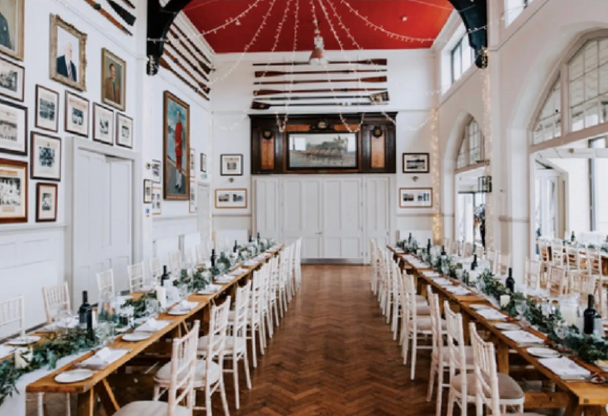Long tables laid the length of the hall for a dinner, blades overhead and crew photographs down the walls