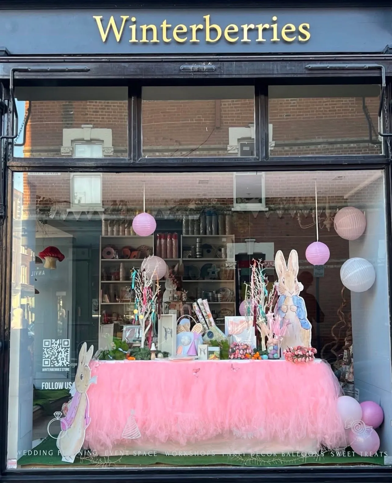 The Winterberries shopfront on Fulham Road, its gold sign above a window dressed for spring with a tulle-skirted table, paper lanterns and painted rabbits